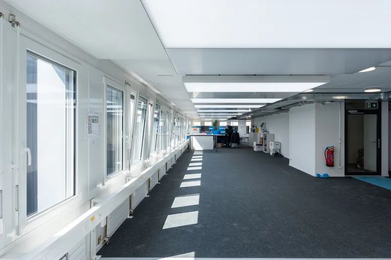 Flur mit Fensterfront und interpanel Klimaleuchten im Tageslicht